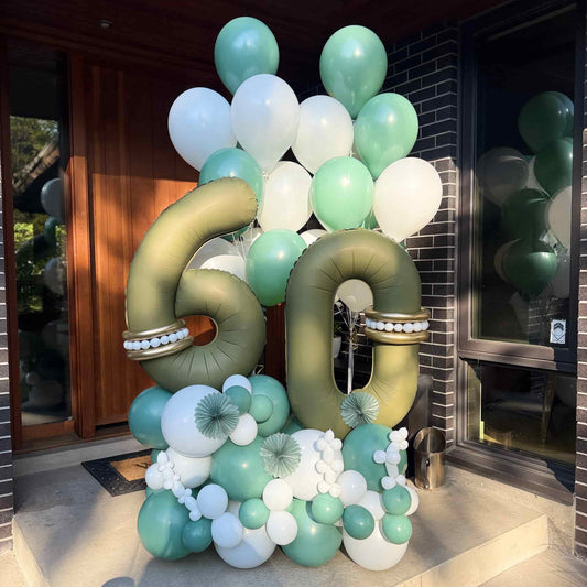 60th birthday balloon arrangement with gold number 60 balloons, sage green and white balloon base and matching bouquet by Wooow Balloons in Toronto.