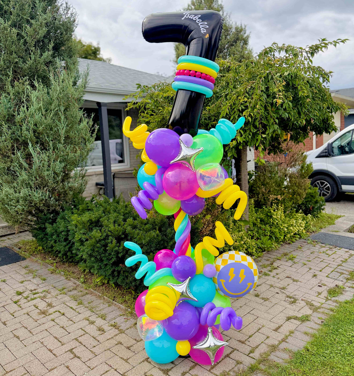 Personalized black number 7 birthday balloon column with turquoise, pink, purple, yellow and green balloons, spiral accents and silver stars in Toronto.