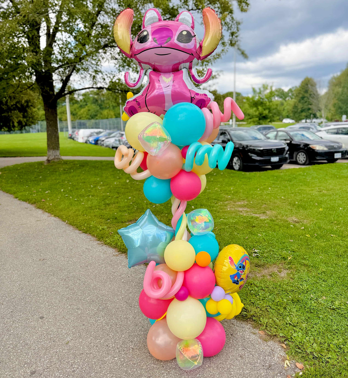 Angel birthday balloon column with pink, turquoise, yellow and peach balloons, spiral accents and a blue foil star by Wooow Balloons in Toronto.