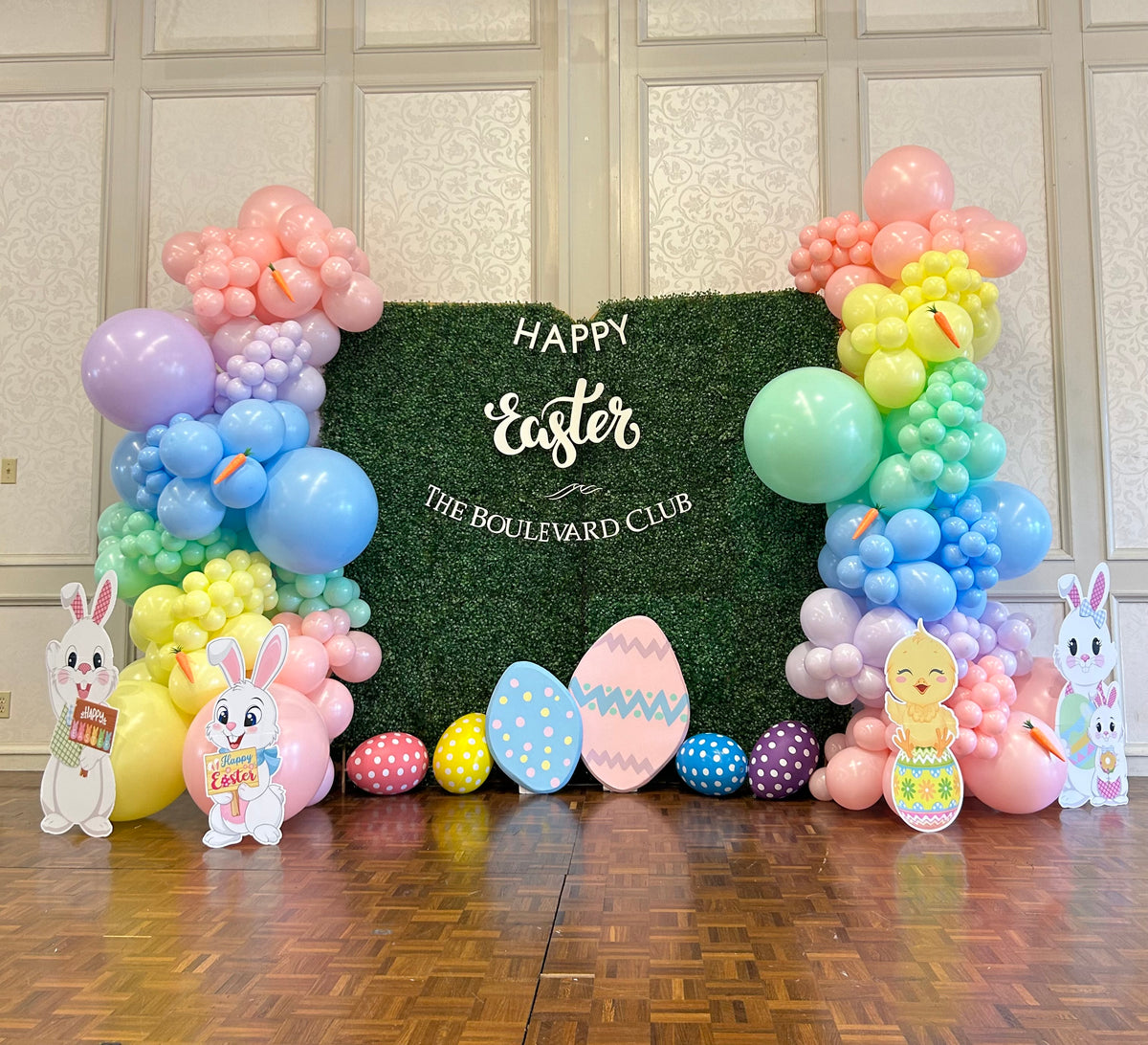 Easter Balloon Set-Up with Greenery Wall Backdrop, Pastel Balloons, Easter Props, and Eco-Friendly Balloons.