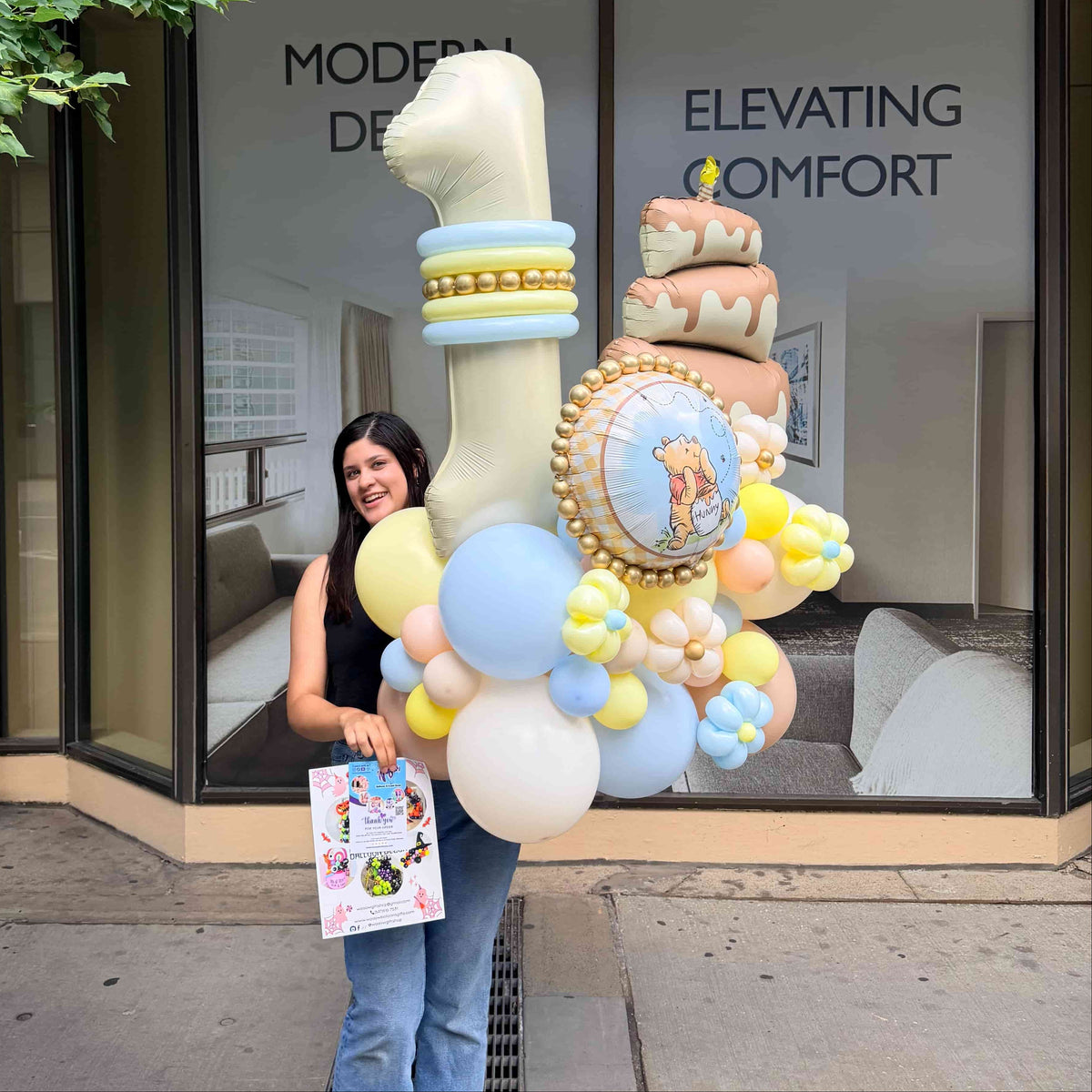 Winnie the Pooh first birthday balloon arrangement with a cream number 1, cake foil balloon, pastel blue and yellow balloons, and balloon flowers in Toronto.