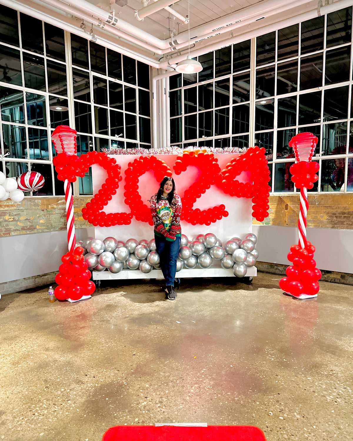 Christmas Balloon Numbers and Light Stands Decor with festive candy cane accents and gingerbread house backdrop.