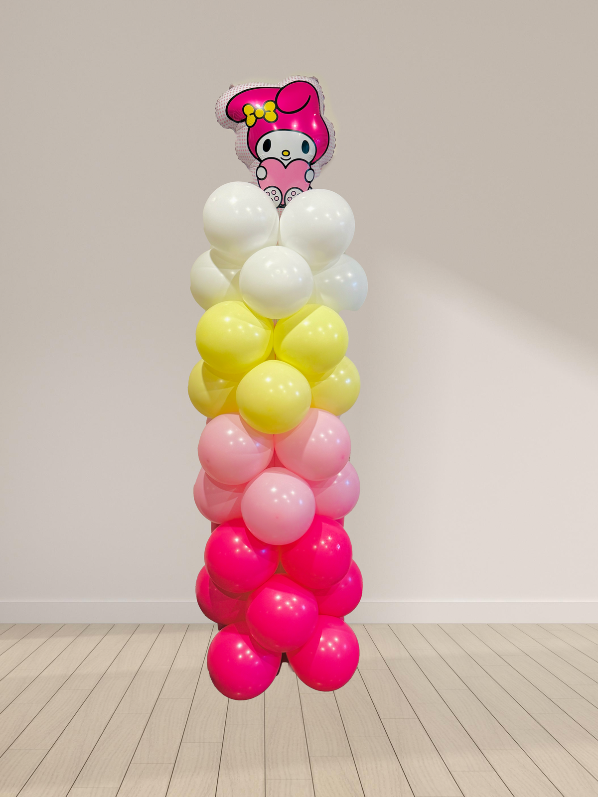 Balloon column with a character balloon on top against a plain wall.