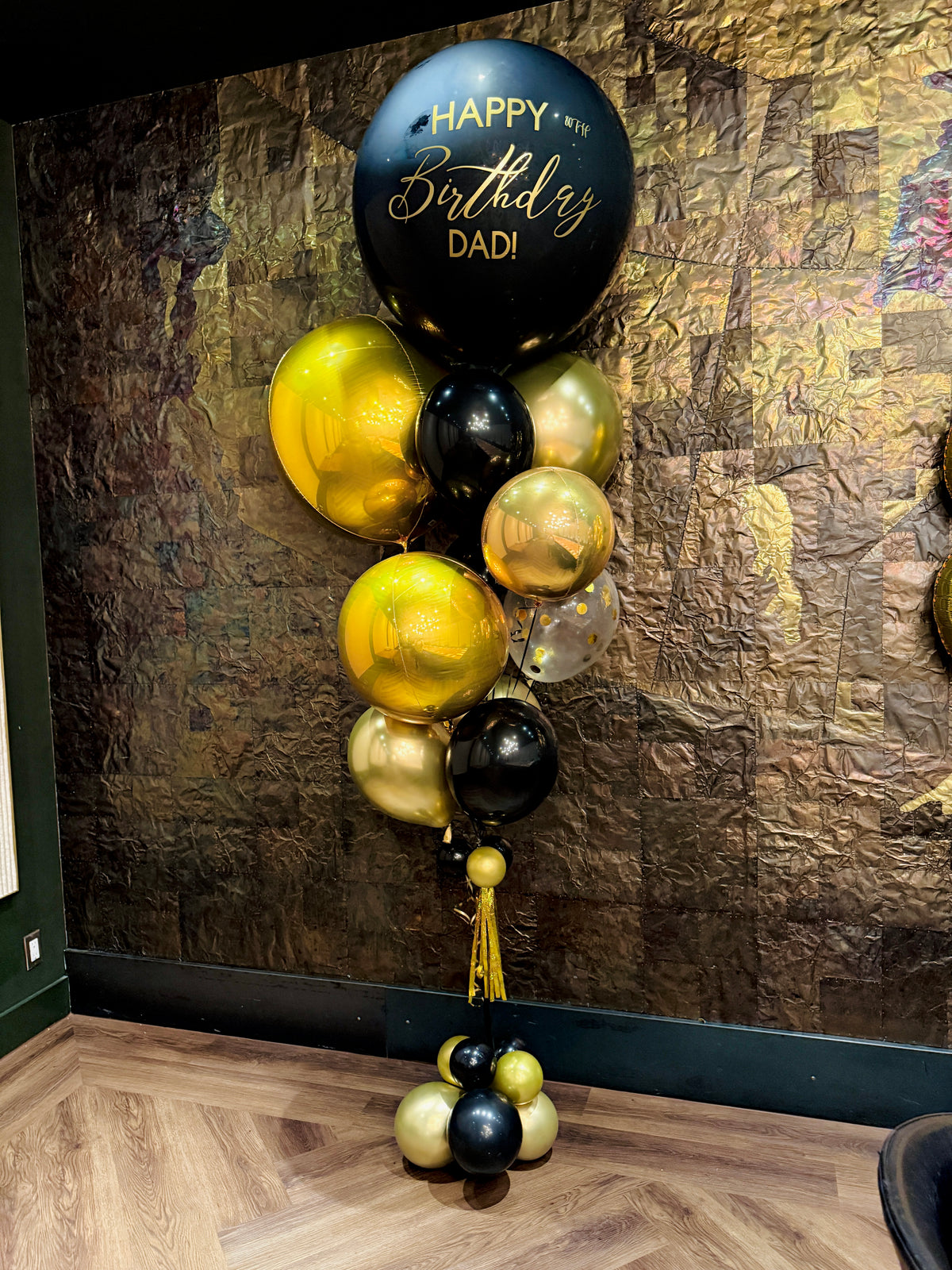 Balloons with 'Happy Birthday Dad!' text against a textured wall.