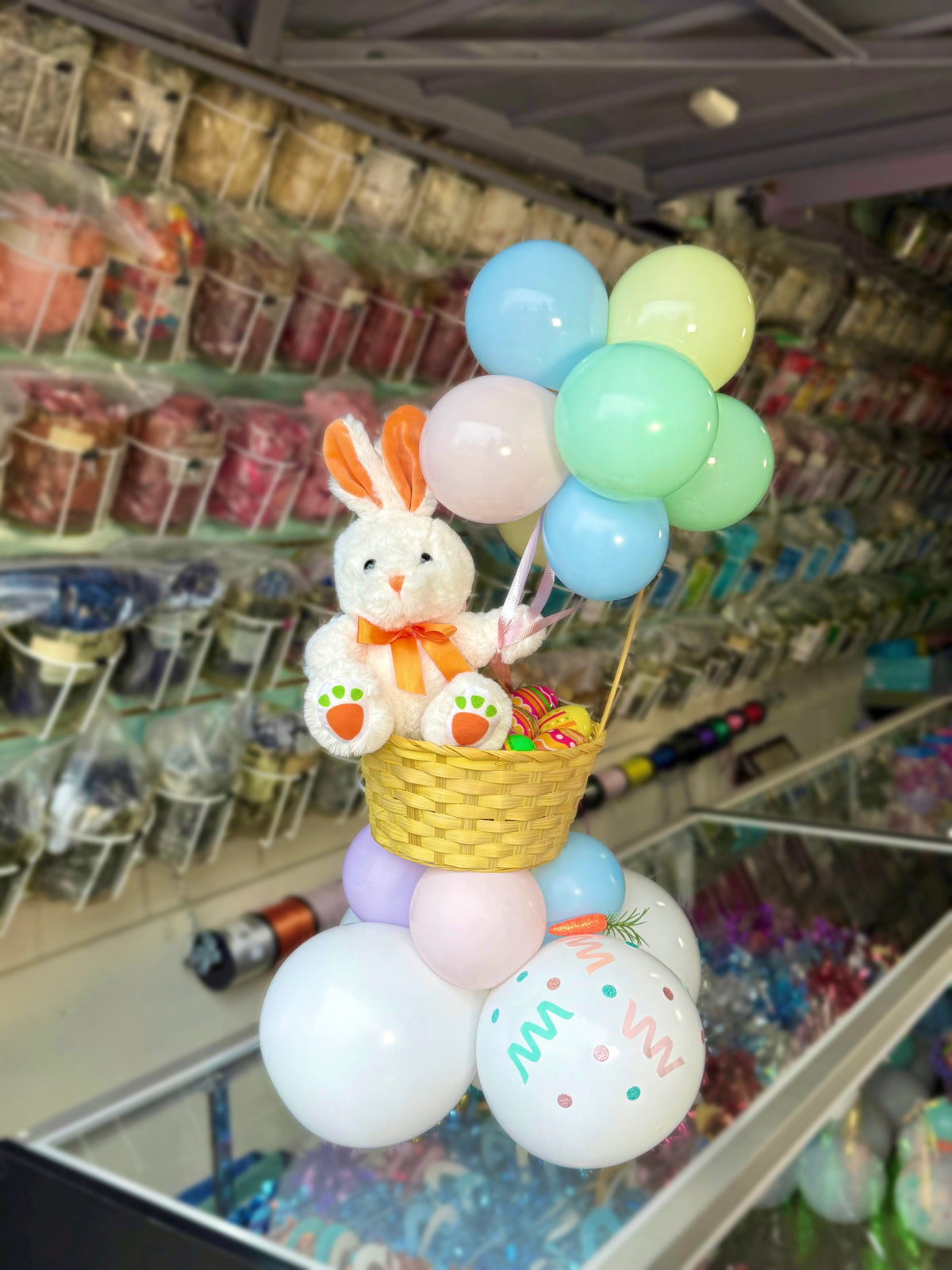 Decorative arrangement with balloons and a plush toy in a store setting
