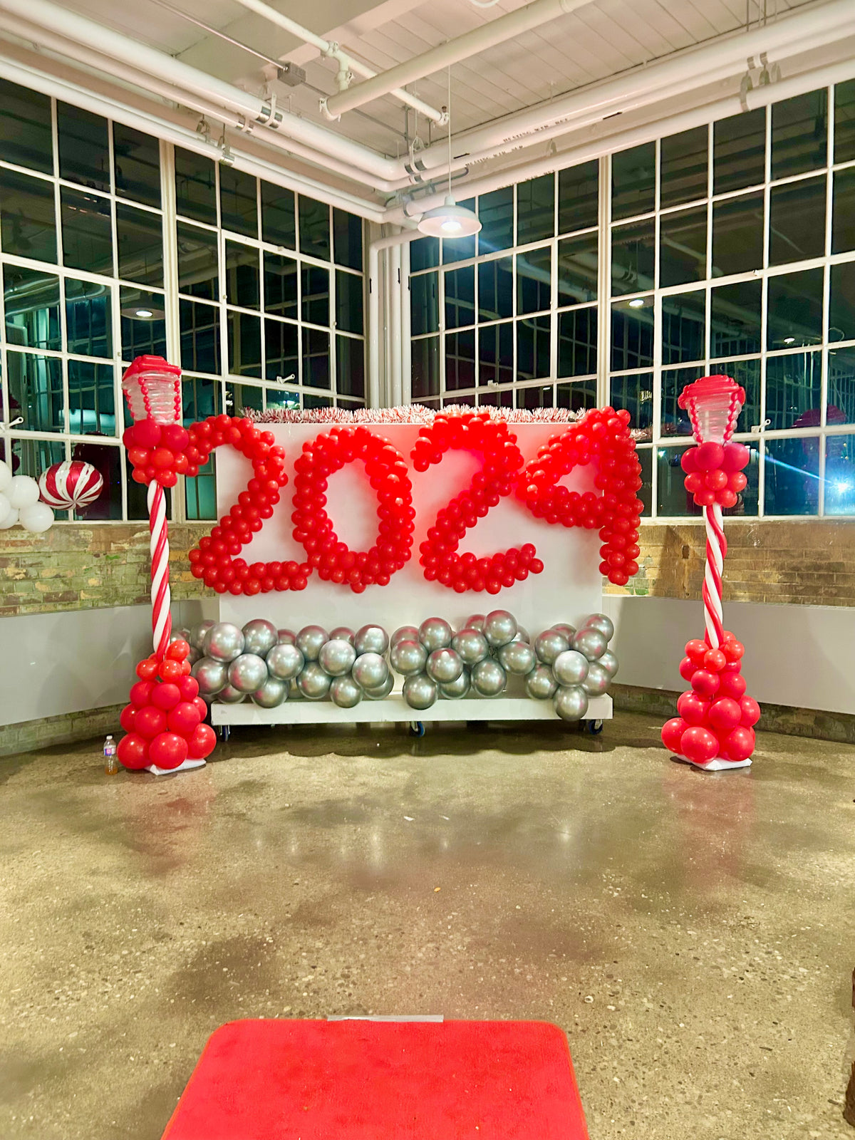 Christmas Balloon Numbers and Light Stands Decor with festive candy cane accents and gingerbread house backdrop.