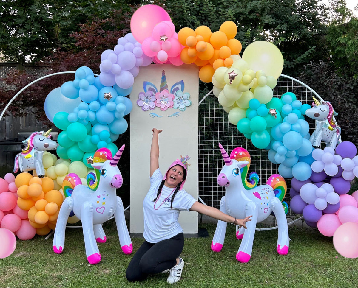 Magical Unicorn Balloon Backdrop with a pastel rainbow balloon arch and inflatable unicorn decorations for a kids’ party.