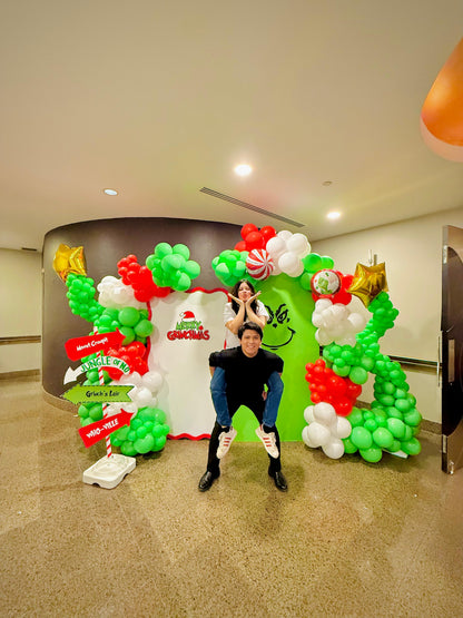 Grinch balloon decor setup with festive balloon garlands and backdrops.

