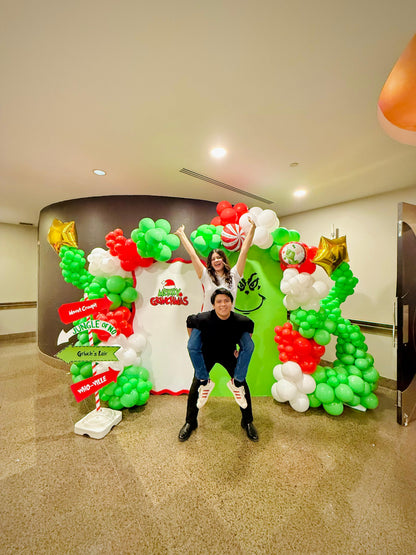 Grinch balloon decor setup with festive balloon garlands and backdrops.

