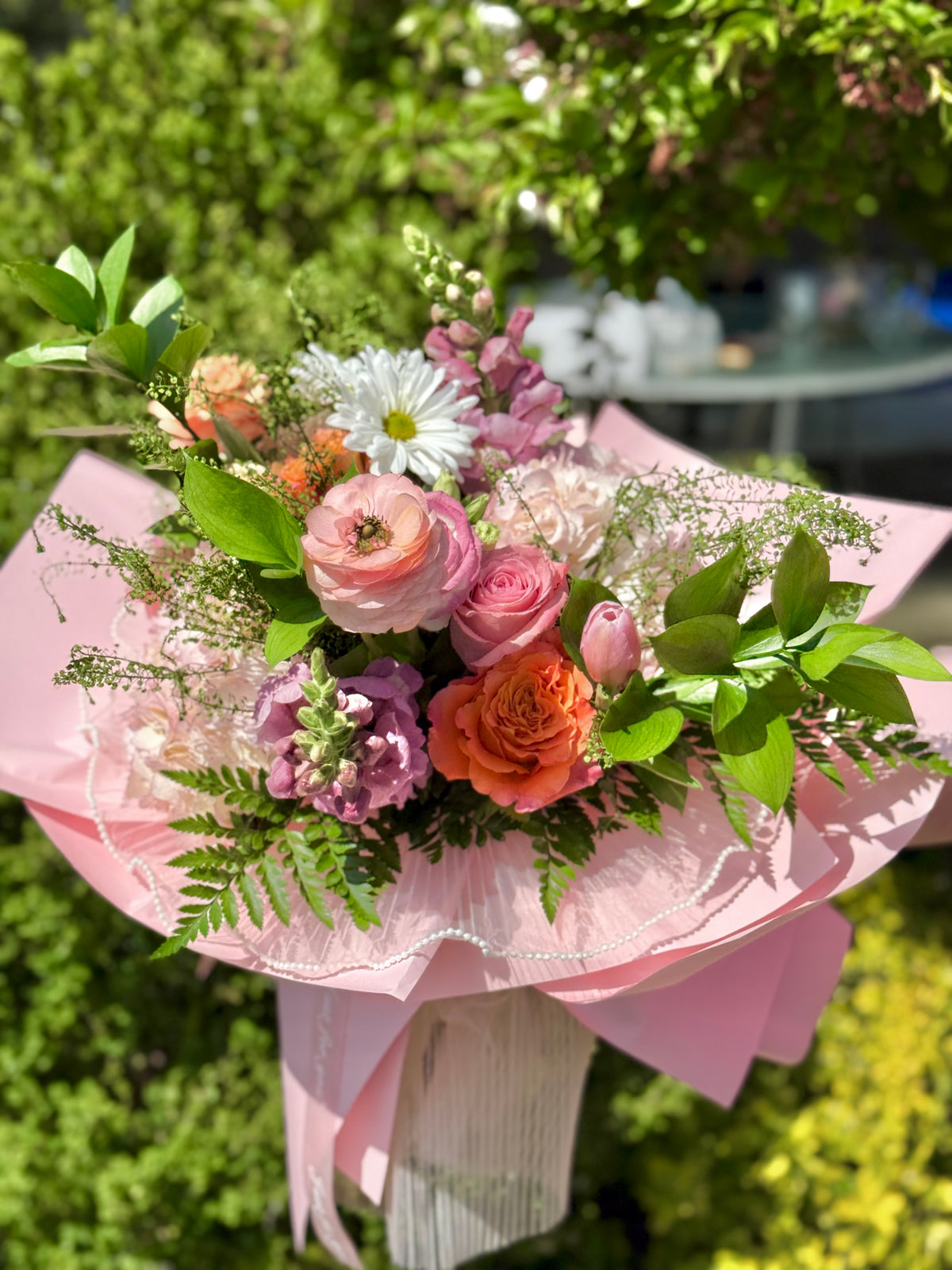 Bouquet of flowers with pink and orange colors wrapped in pink paper.