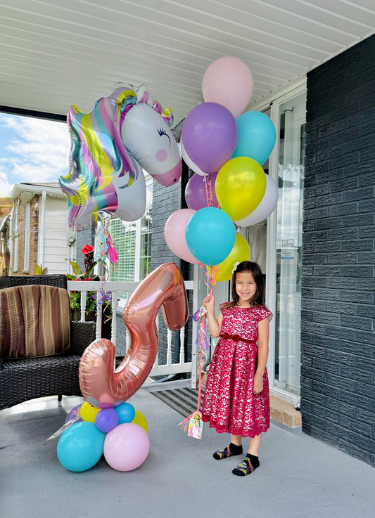 Child holding unicorn balloons with a large number 5 balloon unicorn theme in toronto
