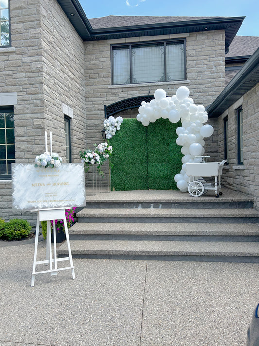 Wedding Balloon Decor featuring a greenery backdrop, organic balloon garland, and floral pedestals with dessert cart.