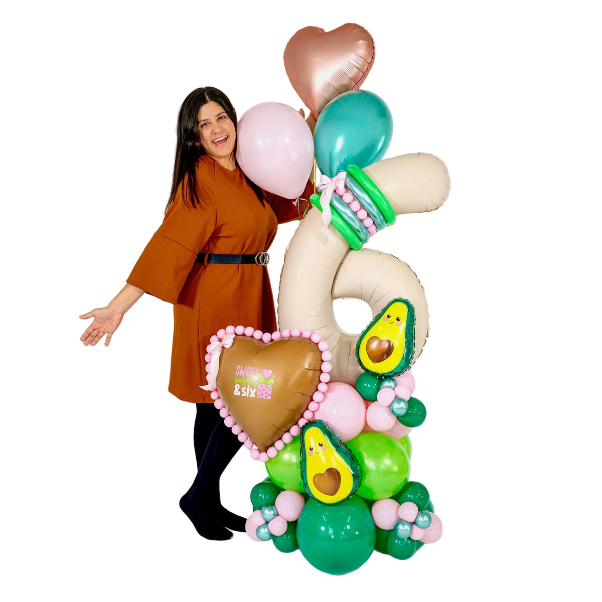 Woman standing beside a tall avocado birthday balloon arrangement with a cream number 6, pink and green base and rose gold heart in Toronto.