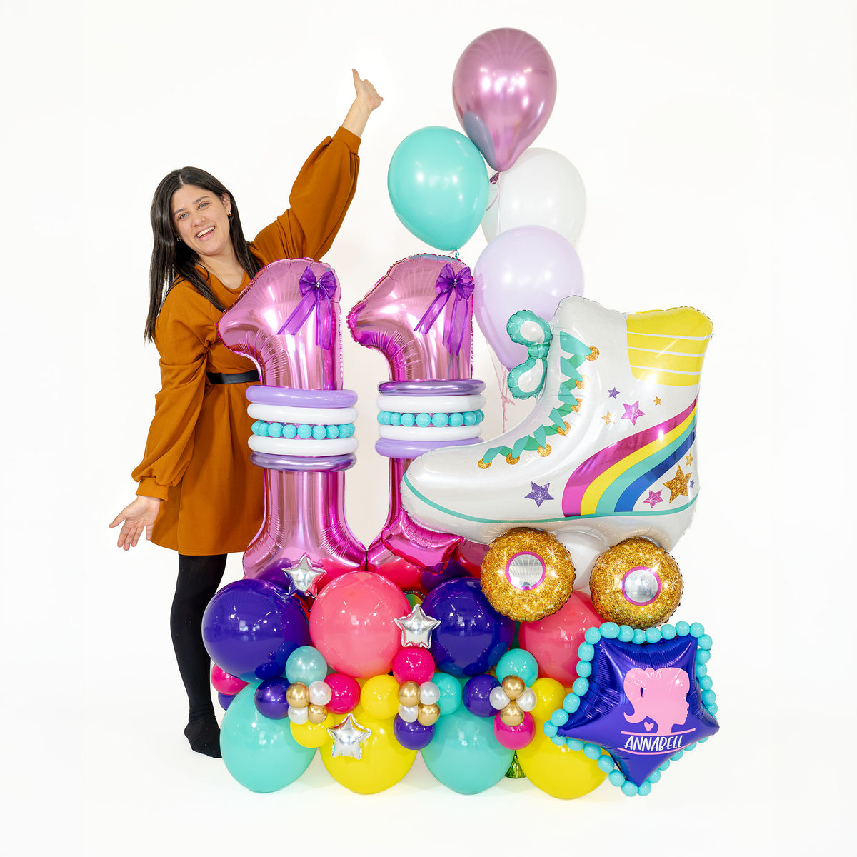 Woman standing beside a personalised Barbie-inspired birthday balloon arrangement with pink number 11 balloons and a rainbow roller skate.