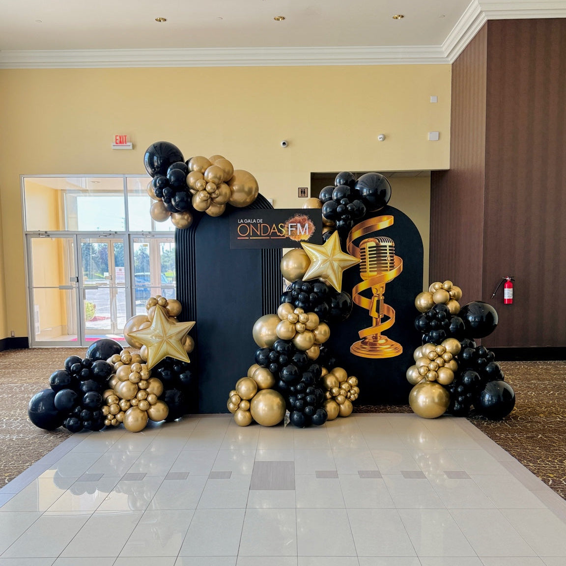 Luxury black and gold gala balloon installation with custom backdrop by Wooow Balloons Toronto.