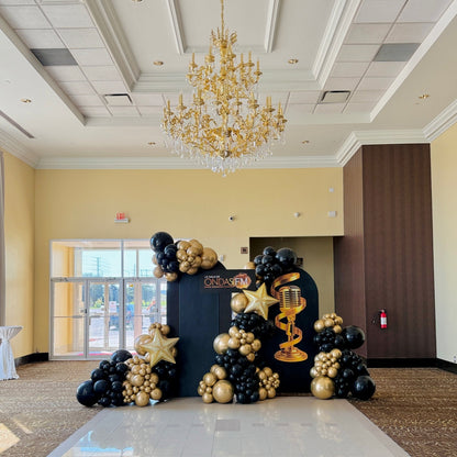 Glamorous black and gold balloon decor with chandelier and custom backdrop for Toronto gala event.