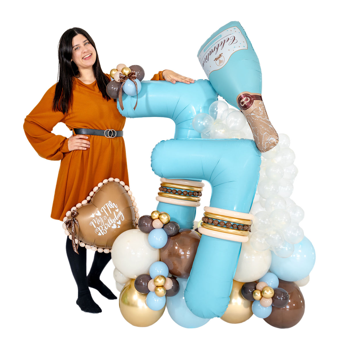 Woman standing beside a large turquoise 77 champagne birthday balloon arrangement with cream, brown and gold balloons
