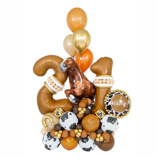 Cowboy birthday balloons by Wooow Balloons in Toronto, featuring bronze number 21, a horse, cow-print balloons and gold western details.