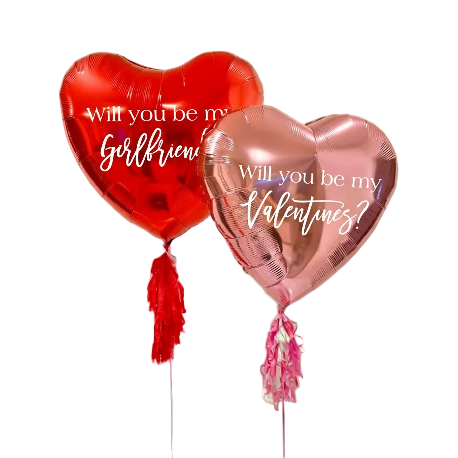 Two heart-shaped balloons, one red and one rose gold, with romantic questions printed on them.