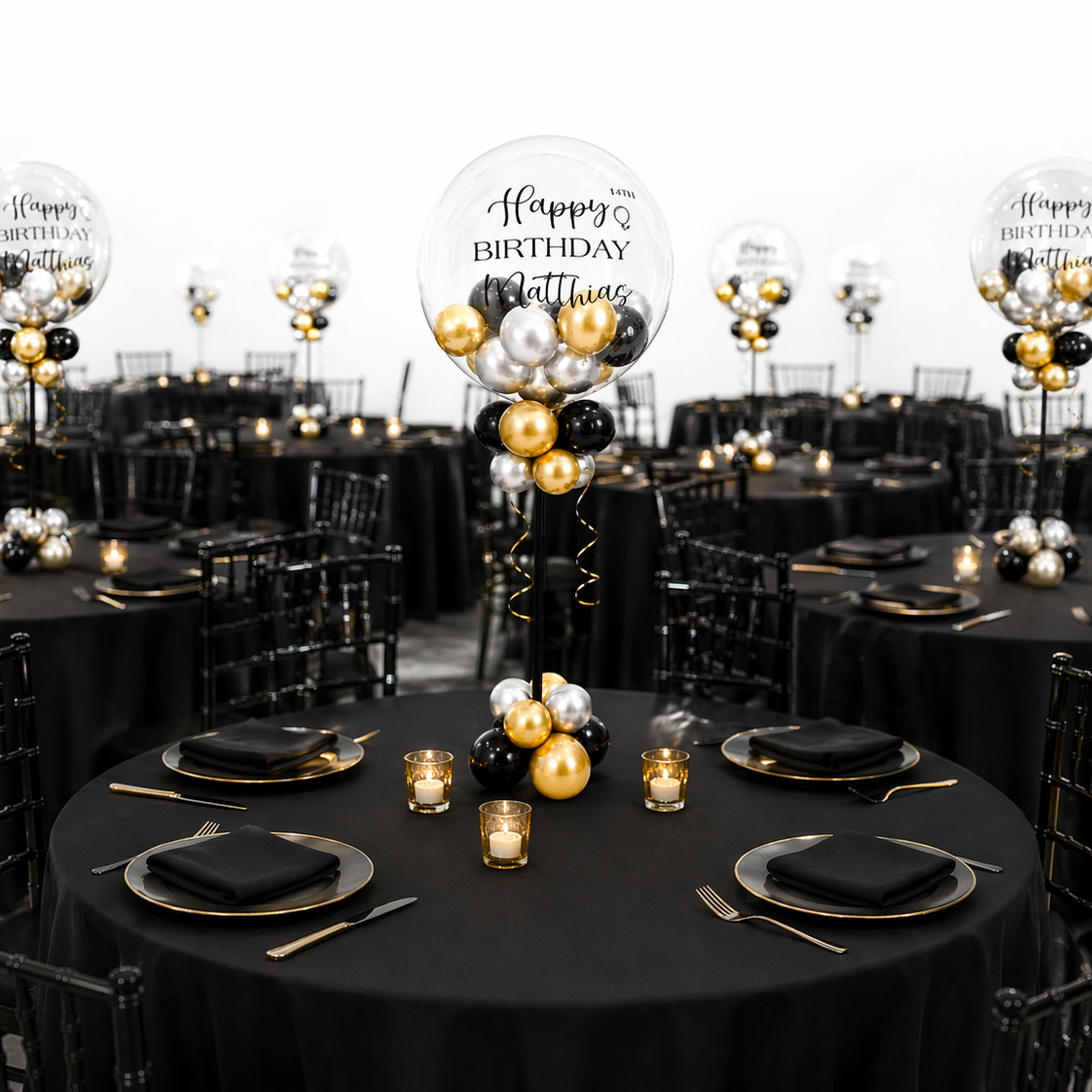Elegant event setup with multiple round tables featuring luxury black, gold, and silver personalized balloon centerpieces for birthday party decor in Toronto.