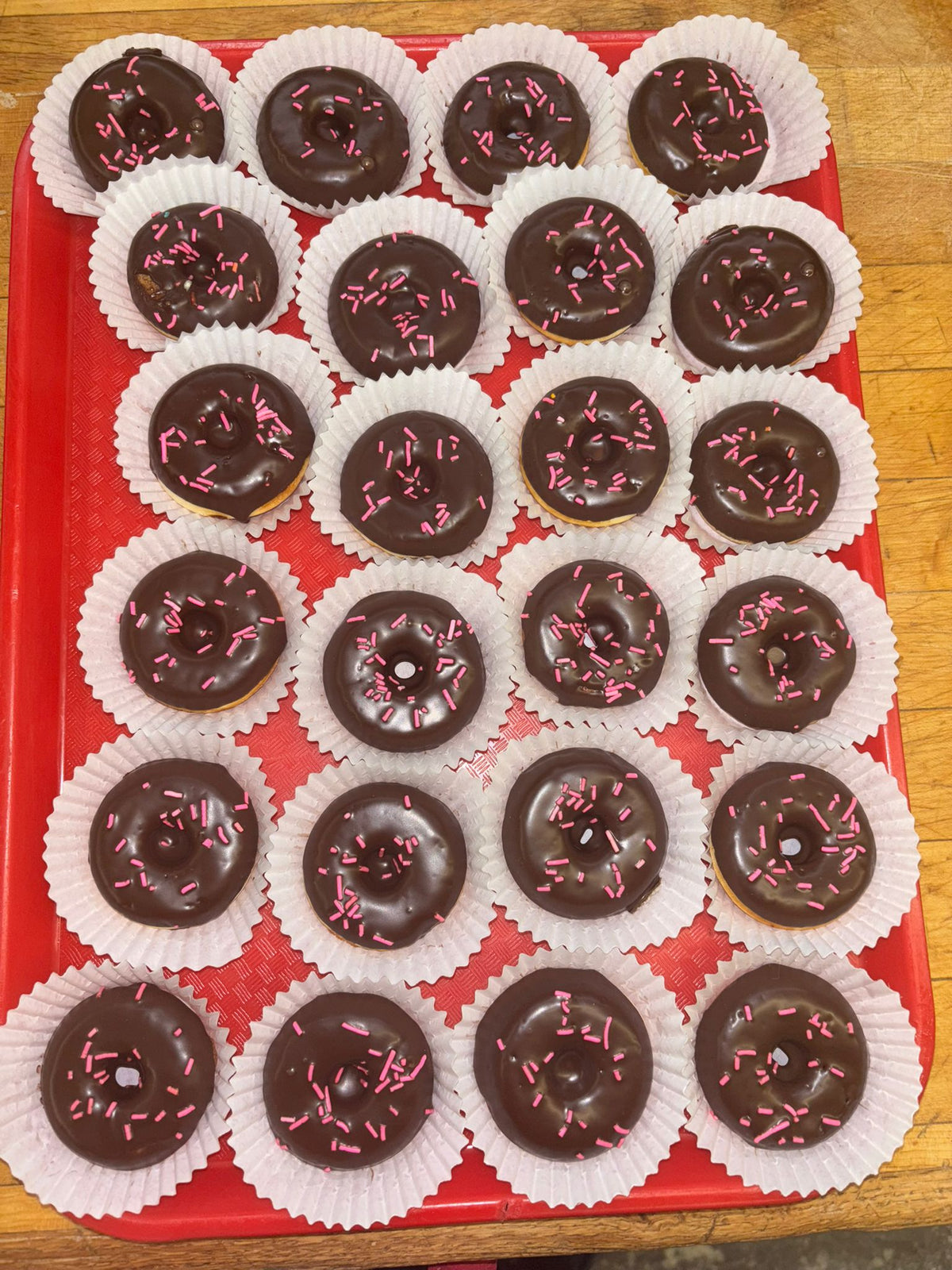 Chocolate donuts with pink sprinkles on a red tray