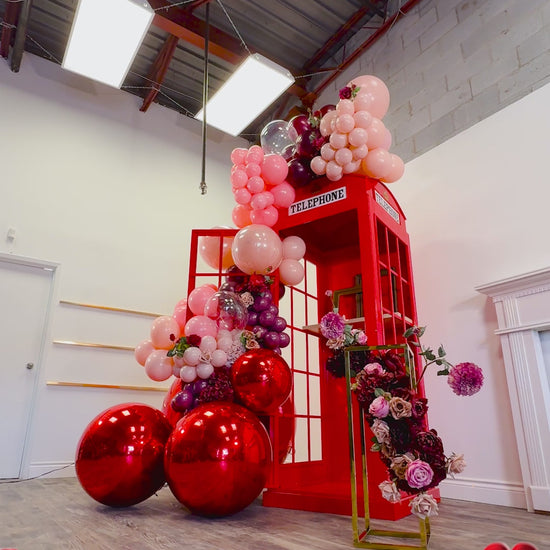 Valentine’s Day Telephone Photo Booth Backdrop Toronto featuring red balloon installation, florals, and statement metallic balloons