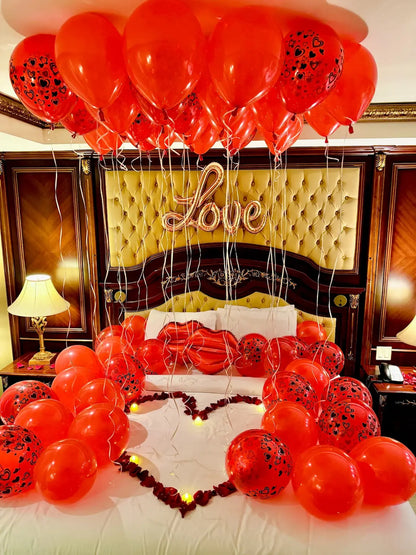 Romantic hotel room decor with red heart balloons and rose petals in Toronto – perfect for couples and anniversary surprises by Wooow Balloons.