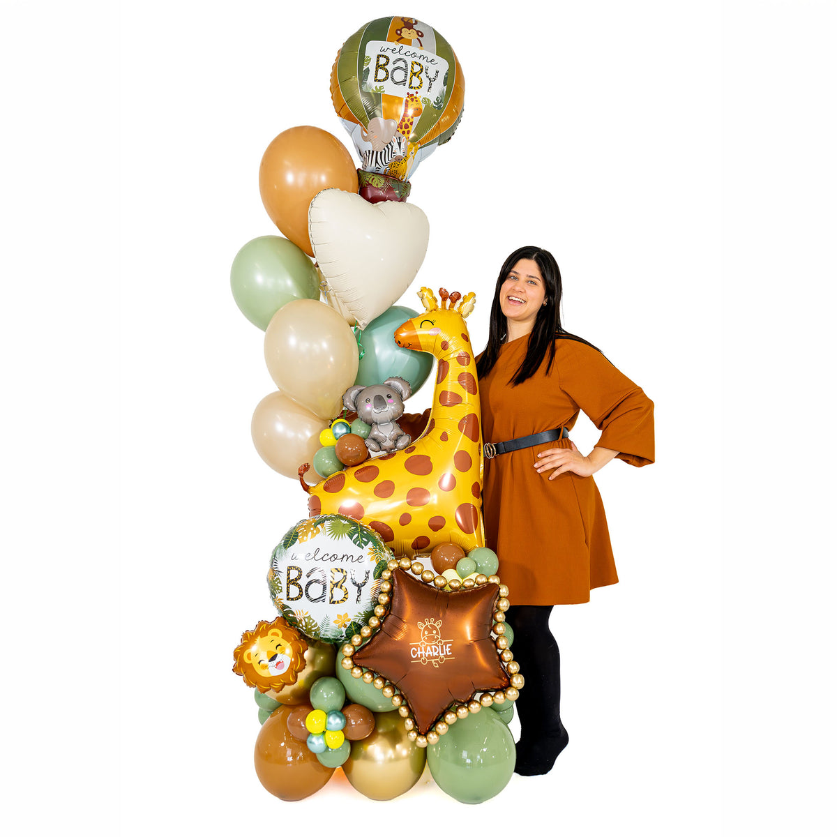 Woman standing beside a tall safari baby balloon arrangement with a giraffe, sage and cream balloons, and a personalized bronze star.