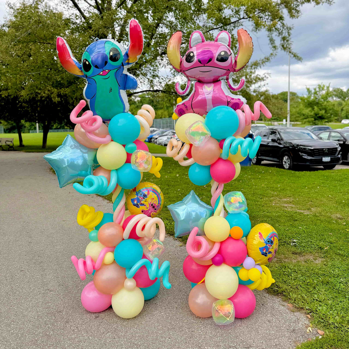 Stitch and Angel birthday balloon columns with turquoise, pink, yellow and peach balloons, blue stars and spiral accents by Wooow Balloons in Toronto.